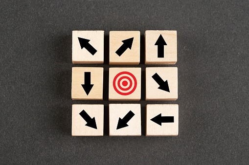 Wooden block cubes with arrows and bull's eye on black background