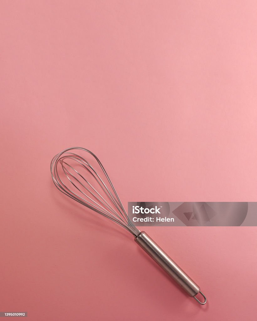 Steel whisk flat lay top view. Confectionery cooking concept with copy space on bright pink paper background. Above Stock Photo