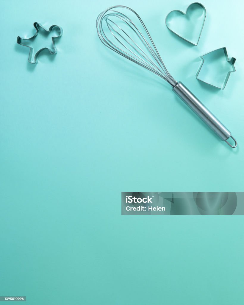 Steel whisk house men and heart shaped cutter flat lay top view. Confectionery cooking concept with copy space on bright cyan paper background Above Stock Photo