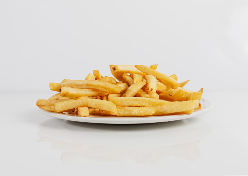 Simple portion of french fries on a plate on a white background, these without sauces ready to serve.