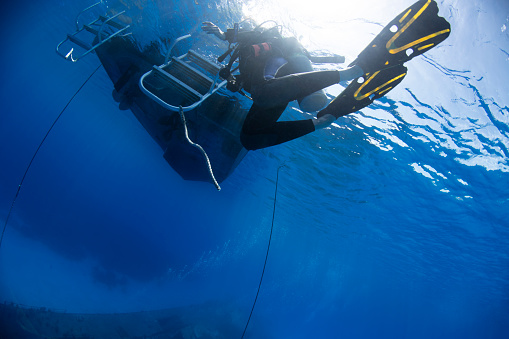 View of a female diver ending a dive and returning to the boat after a wreck dive in Cayman Brac island - Cayman Islands