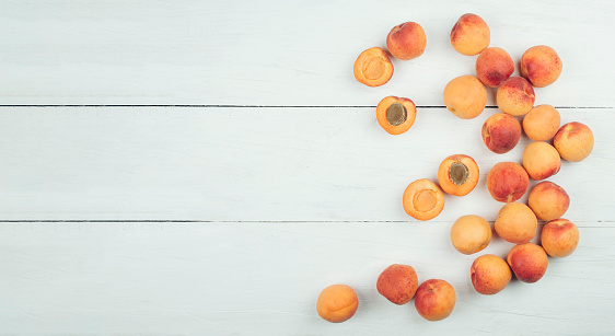 Ripe apricots on rustic background. apricots with leaves on wooden background. Ripe apricots with copy space for text. Various fresh summer fruits. Apricots on a wooden table. Top view.