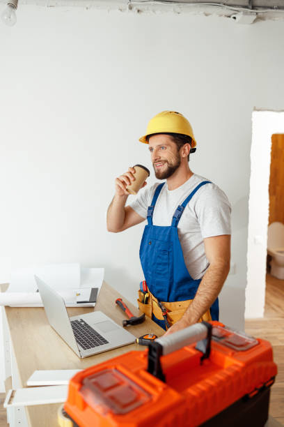 istock Relaxed handyman in uniform and hard hat drinking coffee during a break while doing renovation work indoors 1395015817