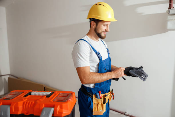 istock Professional electrician technician in uniform and hard hat putting on protective gloves while standing indoors 1395015820
