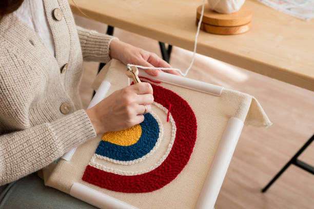 close up of woman creating a handmade decoration for home. female pushing the punchneedle straight down into the fabric. hobby, diy, handycraft concept. new trend in embroidery punch needle. - burlap canvas home decorating color image imagens e fotografias de stock