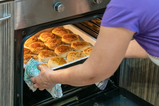 Senior woman backing bun-bread at home.