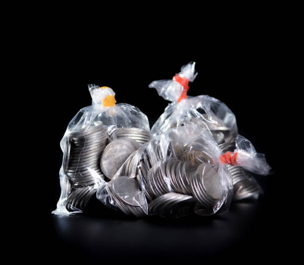 istock coins in plastic bags on black background 1395028653