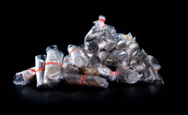 istock coins in plastic bags on black background 1395028658