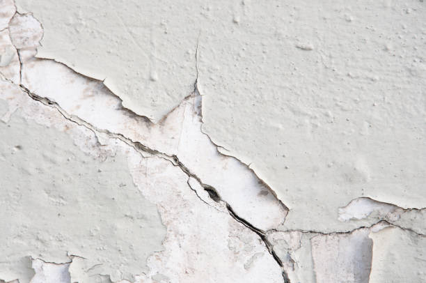 istock Texture of an old concrete light gray painted wall with cracks close up 1395030659