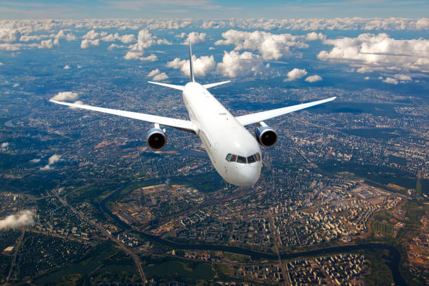 istock White passenger plane flies above the big city 1395033527