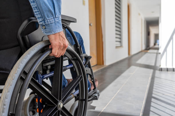 HANDICAPPED DISABLED MAN ON WHEELCHAIR IN A CORRIDOR. INCLUSION IN THE LABOUR MARKET FOR PEOPLE WITH DISABILITIES. CONCEPT OF REMOVE BARRIERS. HANDICAPPED DISABLED MAN ON WHEELCHAIR IN A CORRIDOR. INCLUSION IN THE LABOUR MARKET FOR PEOPLE WITH DISABILITIES. CONCEPT OF REMOVE BARRIERS. paraplegic stock pictures, royalty-free photos & images
