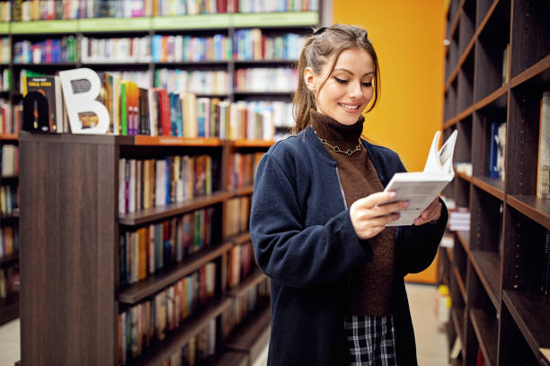 istock Woman reading a book at the library 1395035434