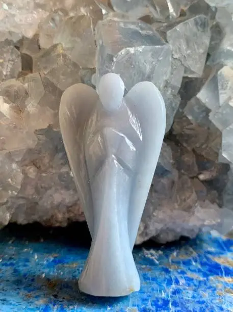 This soft blue angel carved from angelite stands on a gorgeous blue lapis lazuli slab. A heavenly celestite geode adds a soothing blue background.