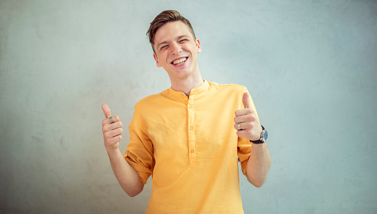 The red-haired boy on a black background with a white shirt holding thumbs up