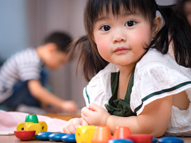 Portrait of cute Asian preschool age girl looking at camera in Montessori classroom Portrait of cute Asian preschool age girl lie on the floor looking at camera in Montessori classroom toddler classes asian stock pictures, royalty-free photos & images