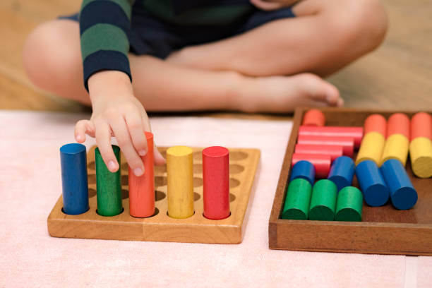 istock Montessori preschool student's hand  learning and playing with wooden cylinder socket. 1395042597
