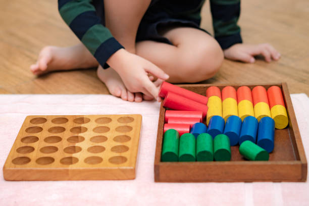 istock Montessori preschool student's hand  learning and playing with wooden cylinder socket. 1395042601