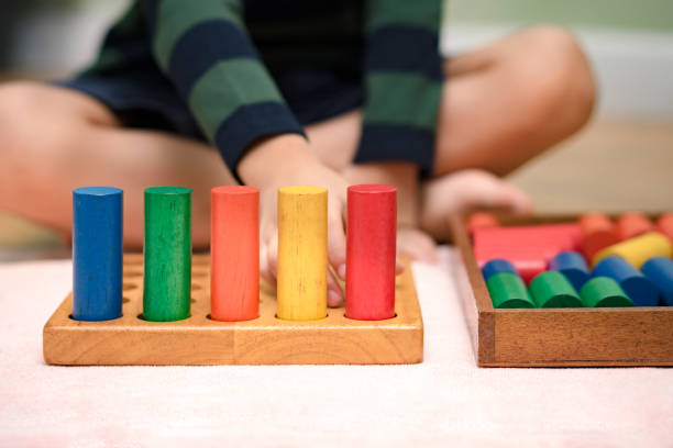 istock Montessori preschool student's hand  learning and playing with wooden cylinder socket. 1395042603