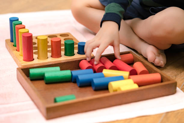 istock Montessori preschool student's hand  learning and playing with wooden cylinder socket. 1395042604