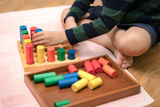 istock Montessori preschool student's hand  learning and playing with wooden cylinder socket. 1395042607