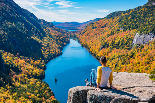 Man enjoys view in the Adirondack Mountains, New York State, USA, during Fall colors.