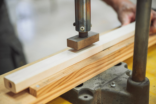 Close up of a stamp about to be pressed onto a pice of wood.