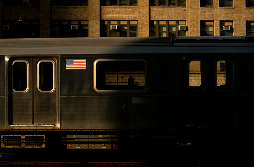 Outdoor subway train in sunlight and shadow.