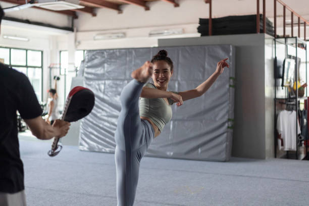 asiatische chinesin, die während des kampfkunstunterrichts das treten übt - karate women kickboxing human foot stock-fotos und bilder