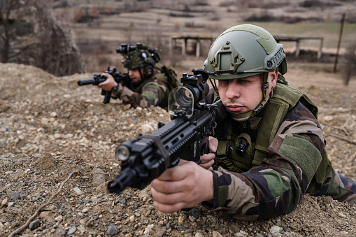 Two men soldiers holding position in the battle war zone aiming rifles dogs of war professional mercenaries or volunteers special forces on a mission attacking or defending enemy copy space