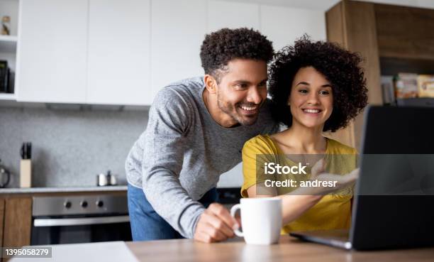 Couple At Home Making A Reservation Online Using Their Laptop Stock Photo - Download Image Now