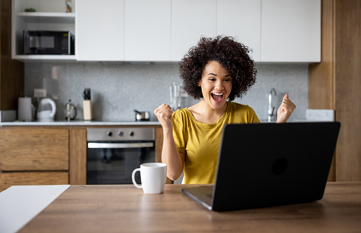 istock Excited woman at home working on her laptop and winning something 1395058281