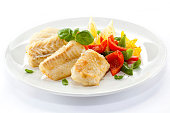 Cod fillets and cooked vegetables on a white plate