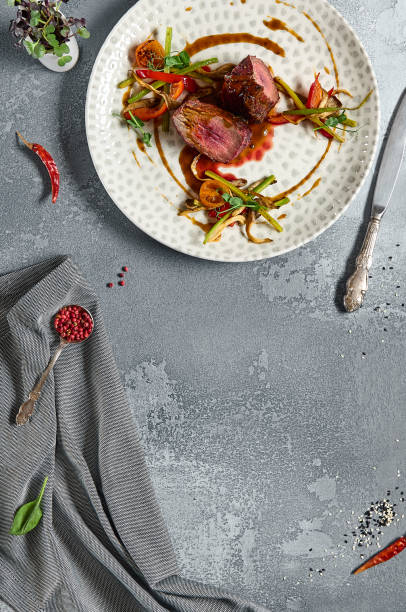 istock Roasted Beef fillet with vegetables. Roasted Mignon steak with paprika and celery. Beef tenderloin with garnish. Beef steak medium rare doneness. Delicious meat menu. Dish concept with angus beef. 1395060469