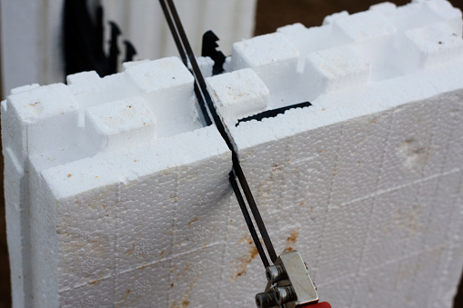 Using a hot knife to cut (melt)  through a polystyrene ICF (Insulated Concrete Form) block to cut it to the desired length.