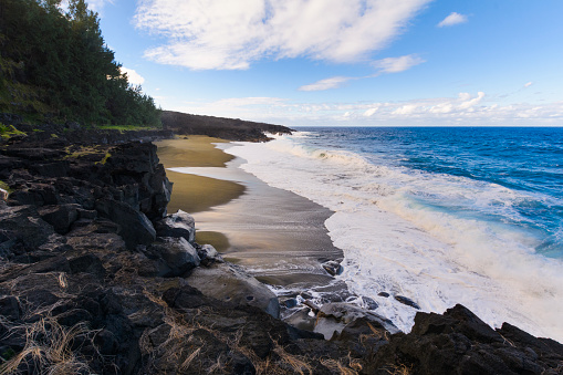 Wild beach with volcanic rocks at Reunion Island with a blue sky