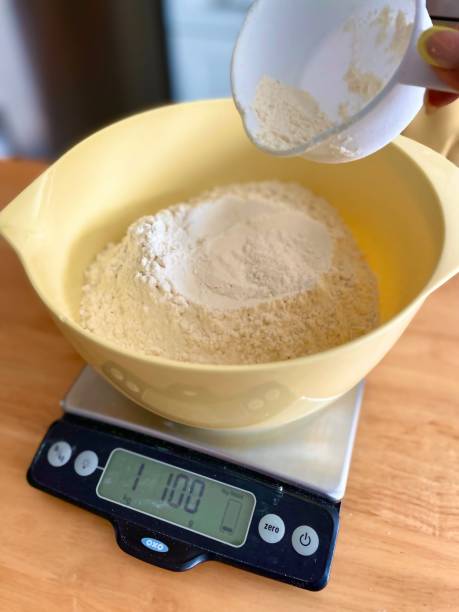 Weighing the flour for sourdough bread Close up shot of flour on a gram scale as it is being poured into bowl. kitchen scale stock pictures, royalty-free photos & images
