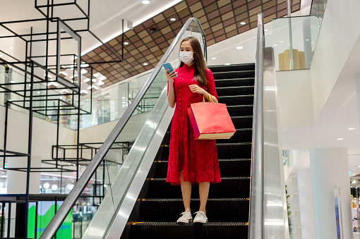 Asian women in red dress (Qipao) shopping in malls on vacation live a new normal in the capital, travel in the capital Epidemic Prevention in Bangkok, Thailand
