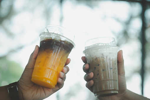 Iced Mocha coffee and iced americano black coffee mix of orange juice in hand. The concept of friendship.