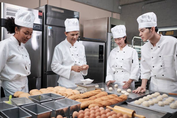 istock Chefs team in uniforms prepare to bake bread and pastry in stainless kitchen. 1395083706