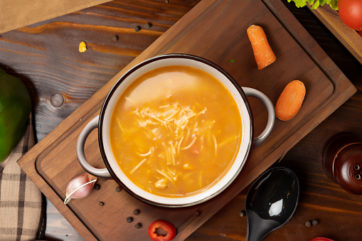 A vegetable soup on a board and carrots in a kitchen environment