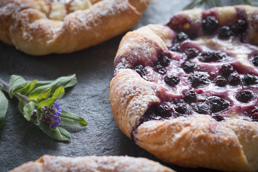 Farm to table - freshly baked blueberry and apple danishes dusted with icing sugar and served on a slate platter.  Vancouver, British Columbia, Canada