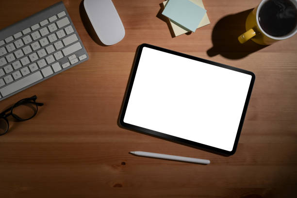 istock Simple workplace with digital tablet, coffee cup, glasses and sticky notes on wooden table. View from above. 1395086983