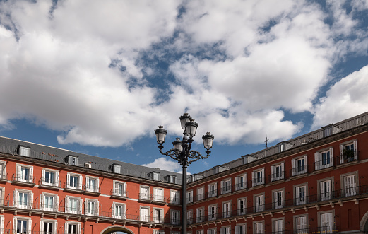 Facade of red building with balconies against cloudy sky. Main Square of Madrid, Spain