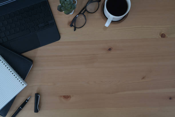 istock Wooden office desk with laptop, glasses, notebook and coffee cup. Top view with copy space. 1395087612