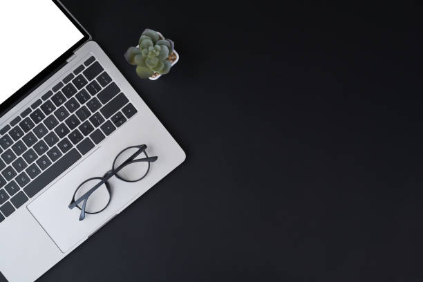 istock Black office desk with laptop computer, eyeglasses and succulent plant. View from above, copy space. 1395087718