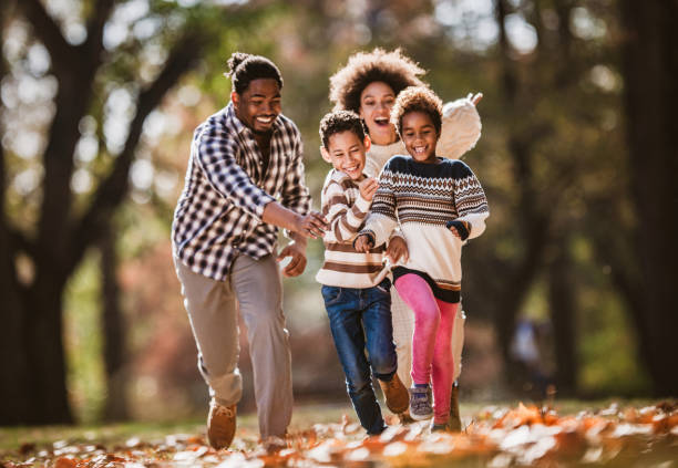 istock Happy black parents having fun while chasing their small kids in autumn day. 1395088662