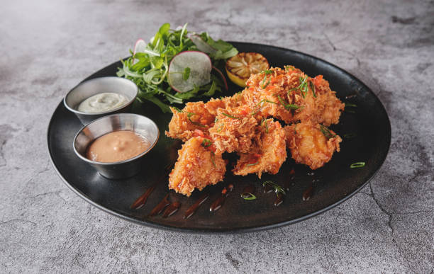istock Crispy fried chicken with gourmet arugula and radish salad, accompanied by Peruvian chili sauces, served on a black plate, Selective focus. 1395090221