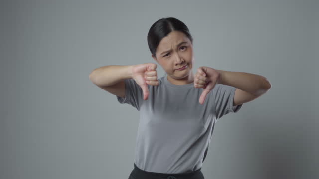 Asian woman annoyed and showing thumb down.