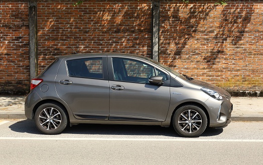 Udine, Italy. April 30, 2022. Gray Toyota Yaris hybrid at the road side. Side view,   brick wall on background