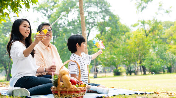 Asian family enjoys a picnic in the garden during their vacation. Grandma, mother and son relax in summer activities. living together and well-being. Concept mother's day stock photo